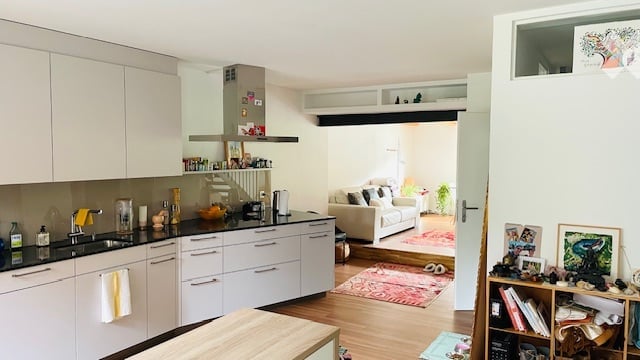 Modern kitchen with white cabinetry, black countertops, island, and modern appliances