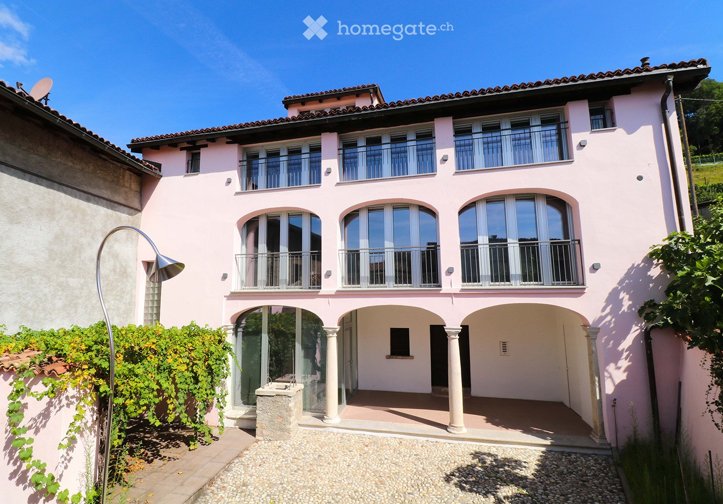 3 story house, pink painted, arched windows, balconies, ground floor with arches