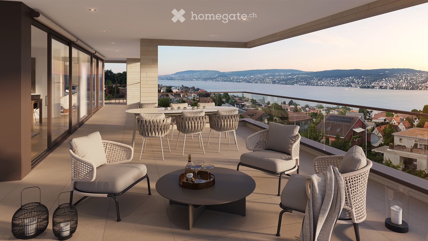 outdoor seating area, glass railing, lake view, wooden table, bottles of wine, chairs, cushions, lanterns, round table