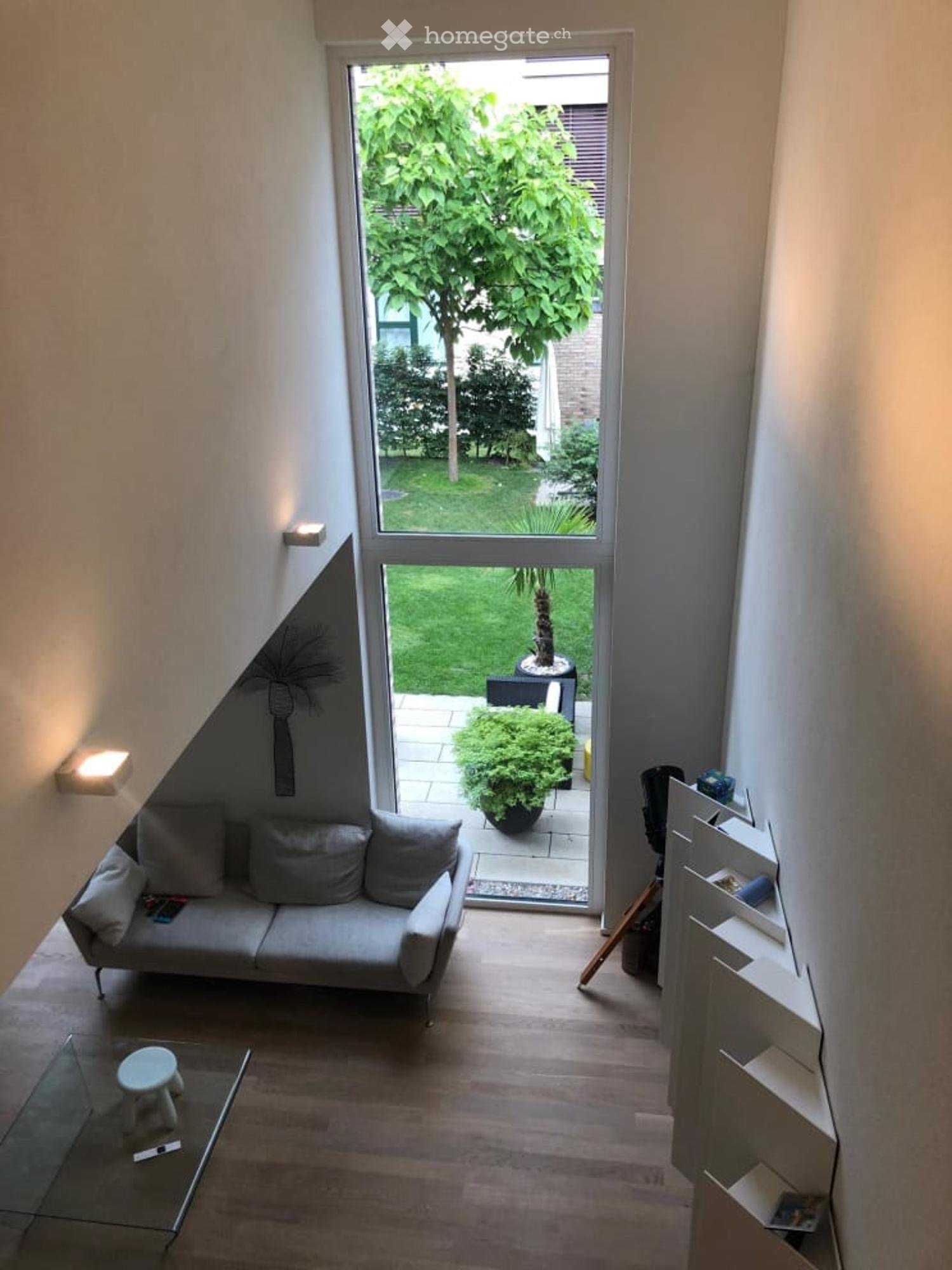 sofa with pillows, glass table, glass doors to garden, tiled floor, white walls, lights