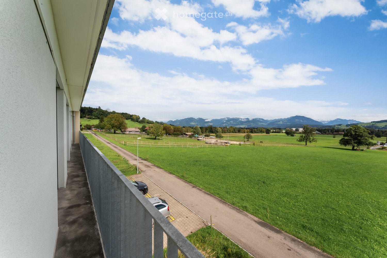 balcony, wide green field, mountains in the background