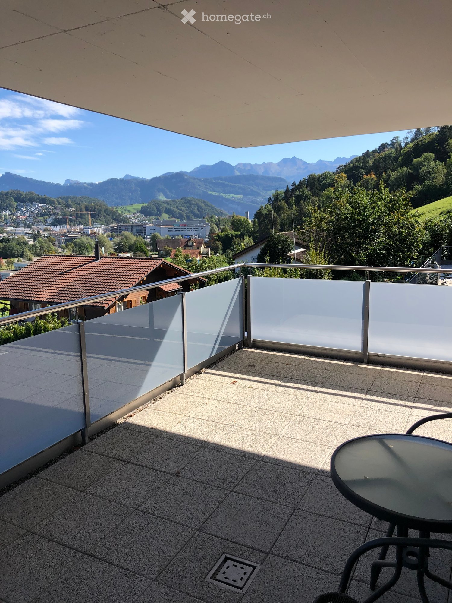 Metal railing, tiled floor, glass wall, round table and chairs