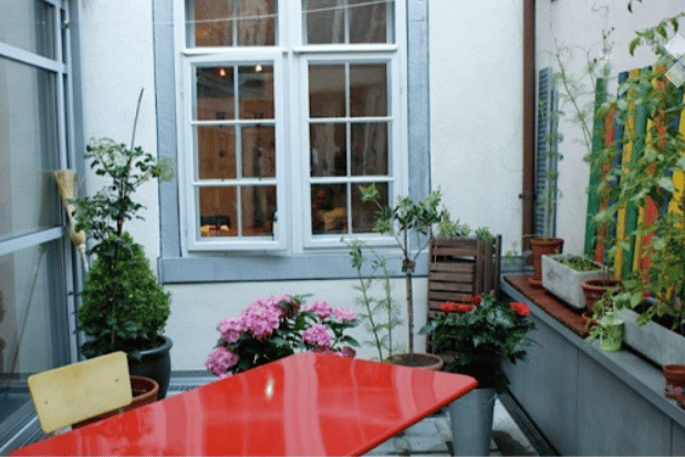 Red table, green chairs, potted plants, window, wall