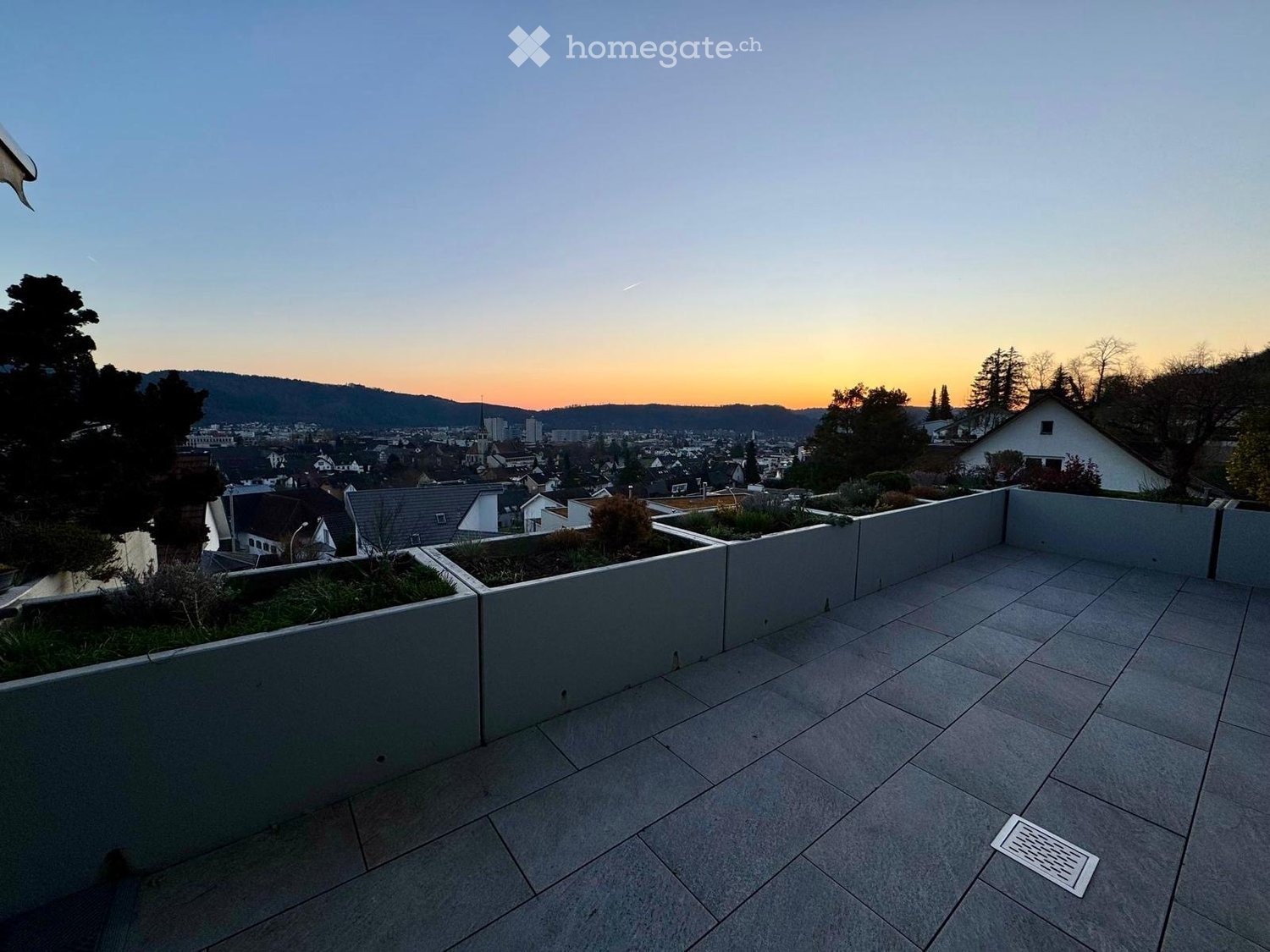 terrace with tiled floor, raised planters, drain, cityscape view, dusk