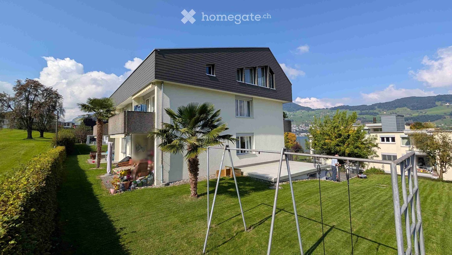 white house with gray roof, terrace on the second floor, garden with grass and trees, balcony on the ground floor
