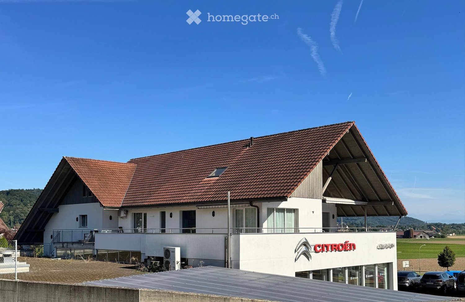 Garage building, 2 story house, red roof, windows, Citroen branding, air conditioners, cars parked in front