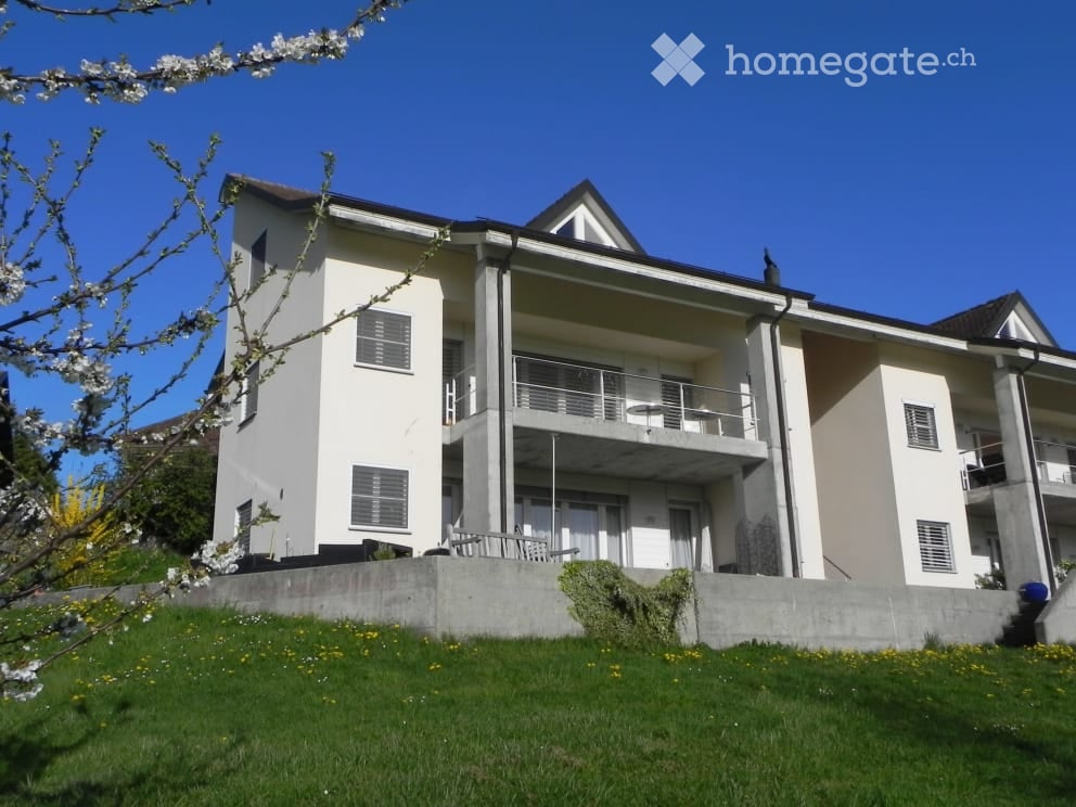 Two story white house, balcony, concrete wall, white window shutters