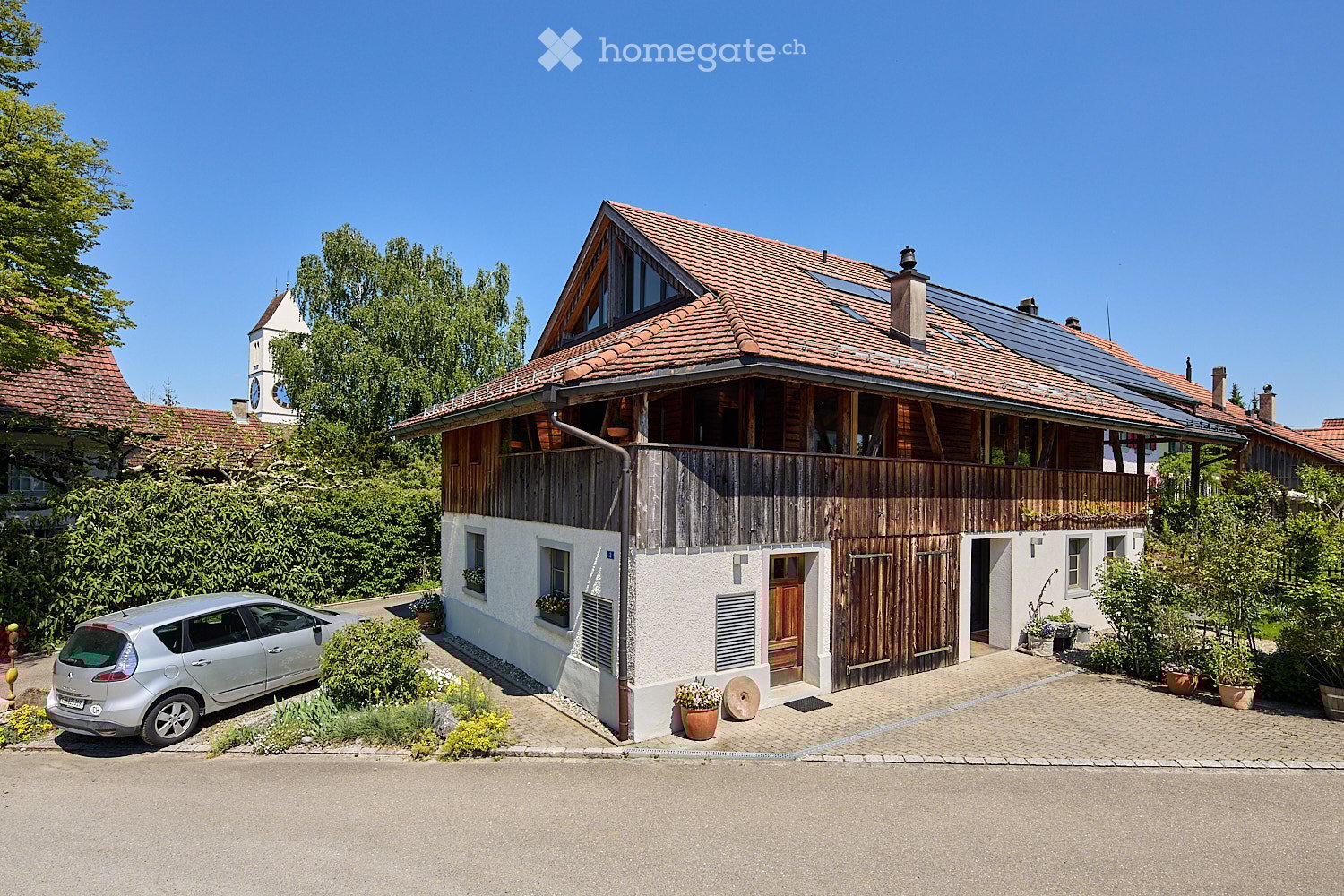2 story house, wooden siding, red roof, solar panels, car parked in front, garden