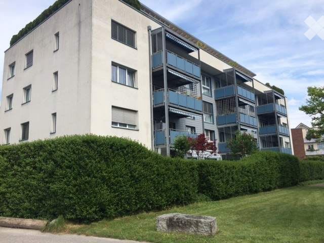 5 story apartment building, white exterior, multiple balconies, green roof