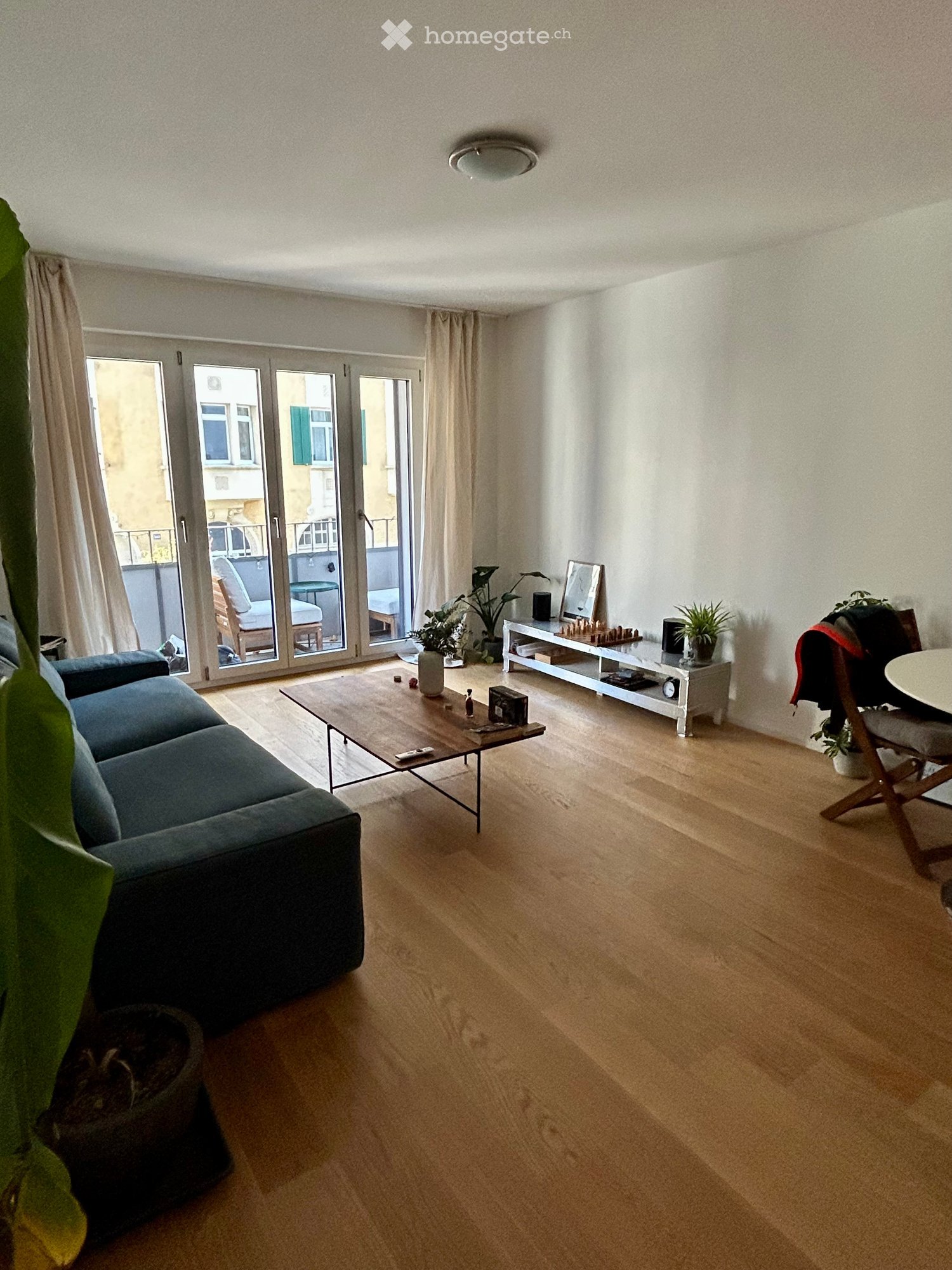 Living room with balcony, hardwood floors, sliding doors leading to balcony, modern decor, sofa, center table, plants