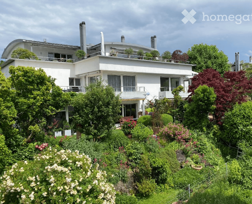 a modern two story house, white exterior, three visible chimneys, large terrace with balcony, lots of greenery