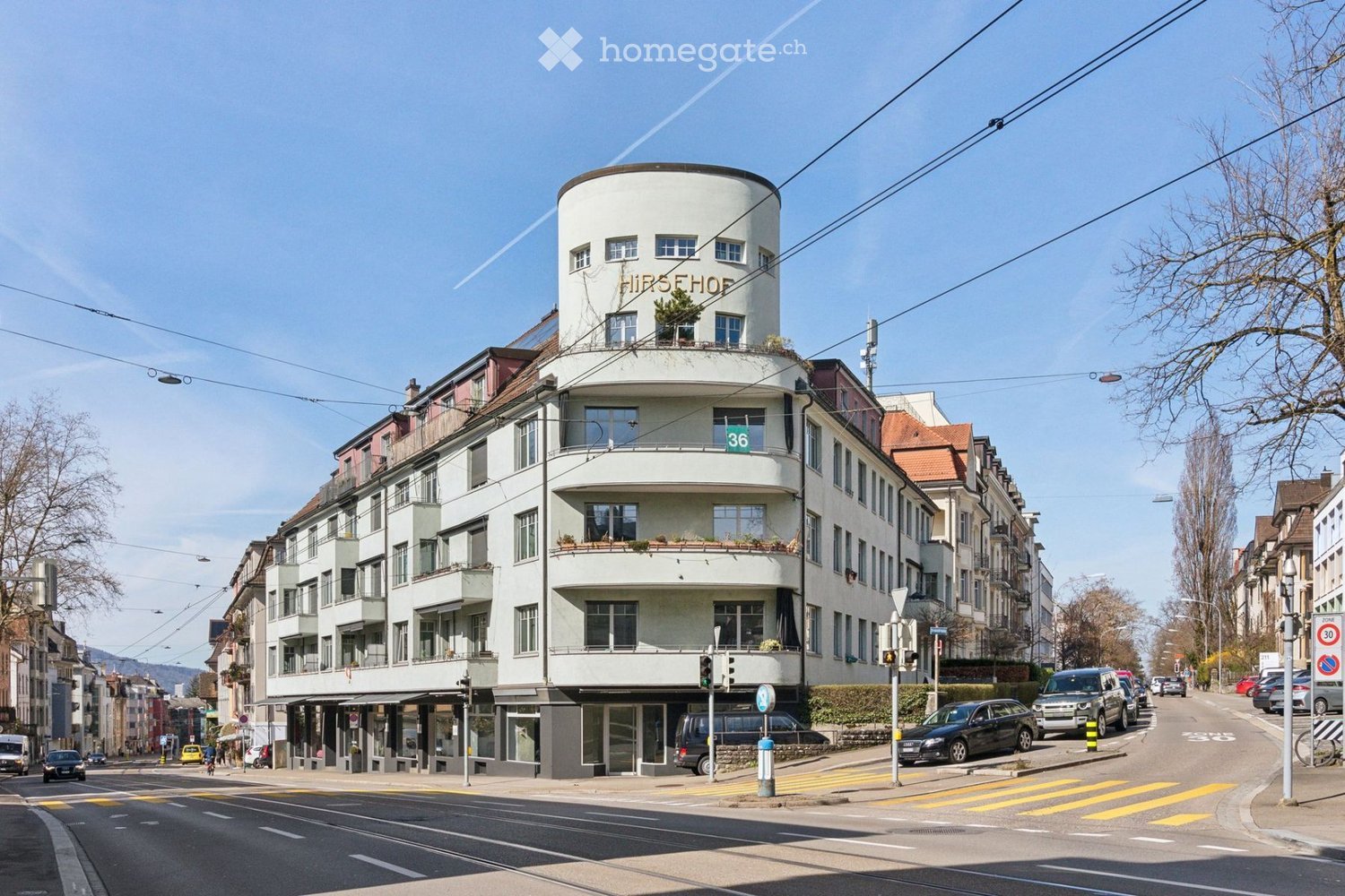 4 story building, round upper section, several balconies, several windows, ground floor with shops