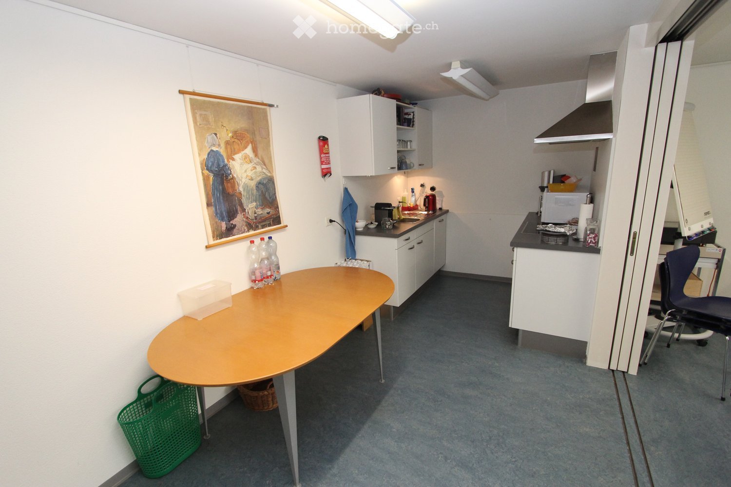 A small kitchen with a large round table, a microwave, sink, and stove.