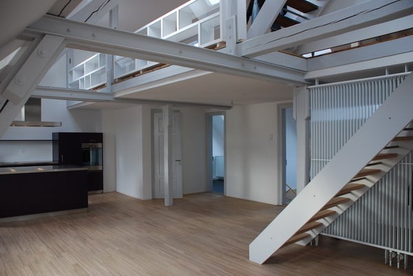 Open concept with exposed trusses, hardwood floors, open kitchen with black counters