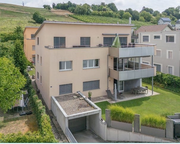 2 story house with a terrace, balcony, and garage, surrounded by trees and greenery