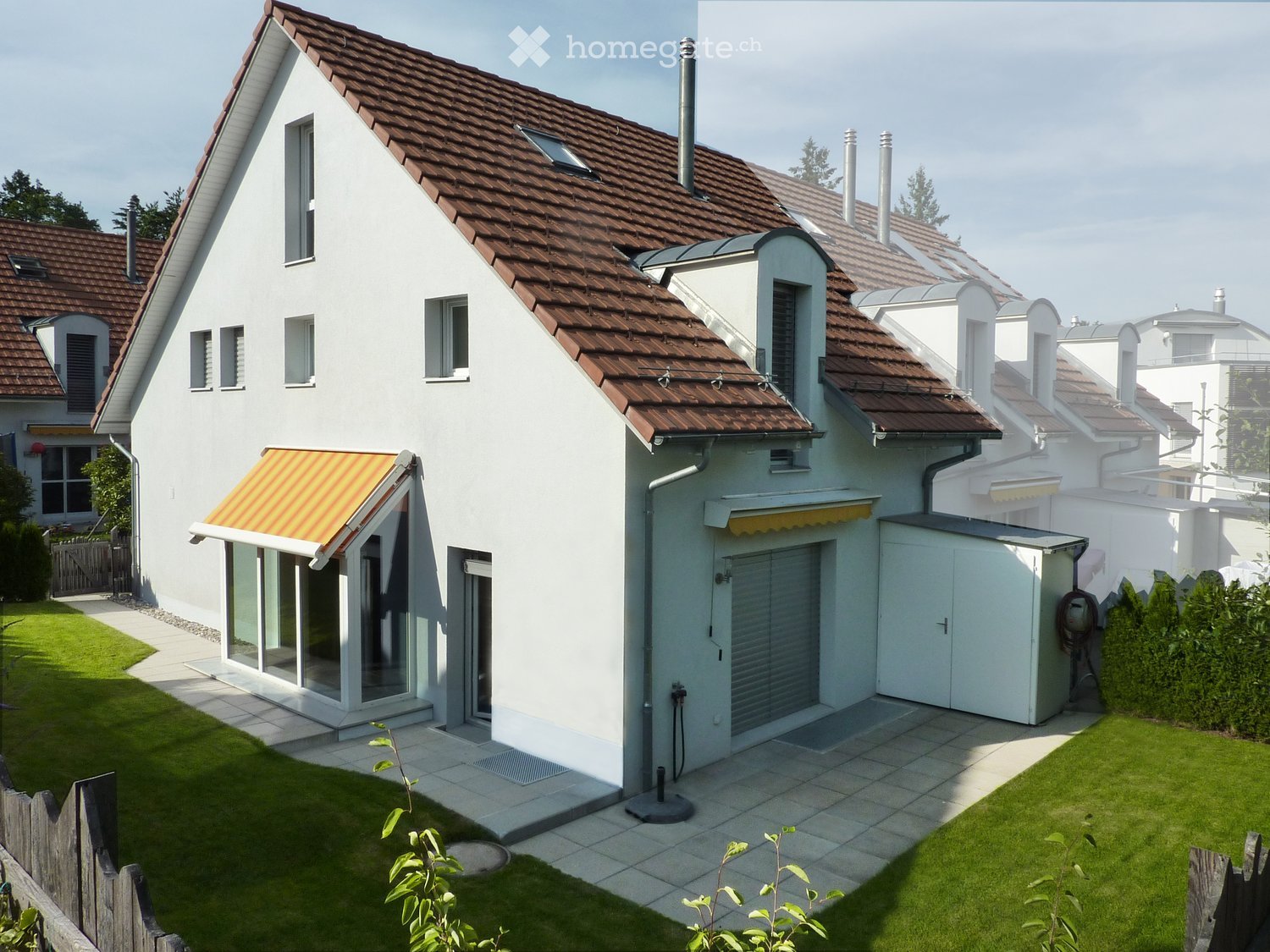 Detached house, brown roof, white facade, garage, yellow awning, paved patio, garden