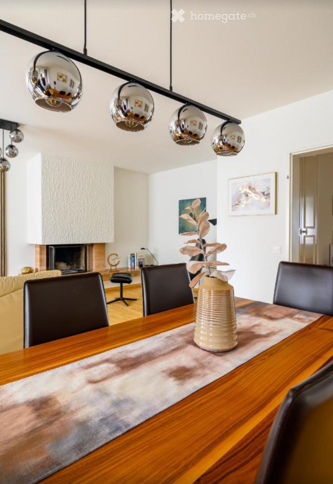 dining room, wooden dining table, dining chairs, ceiling lamp, vase with dried plant, fireplace, white walls