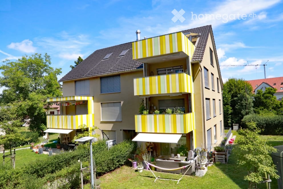Two story apartment house, yellow and white stripes, awnings, balconies, garden