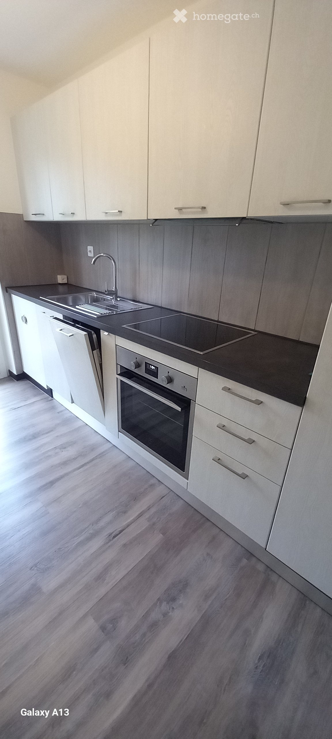 white cabinets, gray laminate floor, stainless steel sink, dishwasher, oven, granite countertop