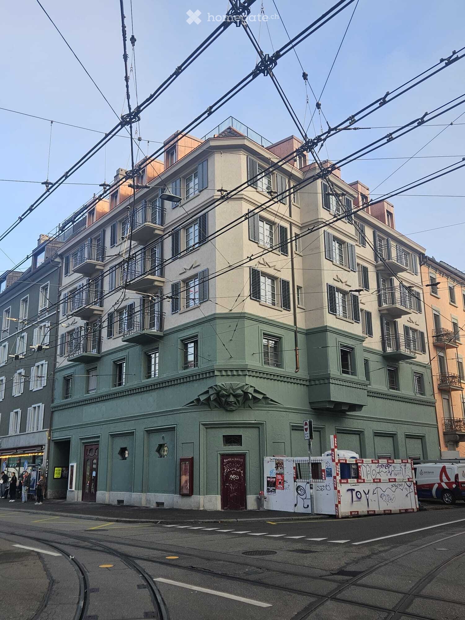 5 story building, white windows, multiple balconies, green wall, multiple doors