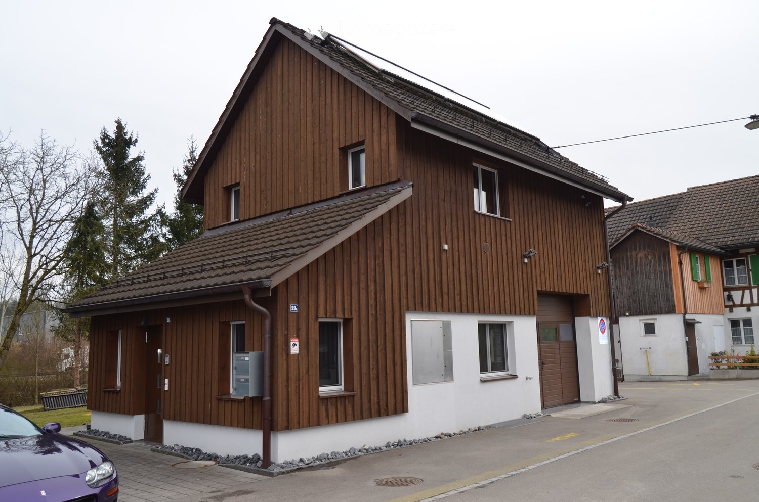 Wooden 2 story house, garage, metal siding, brown roof, multiple windows