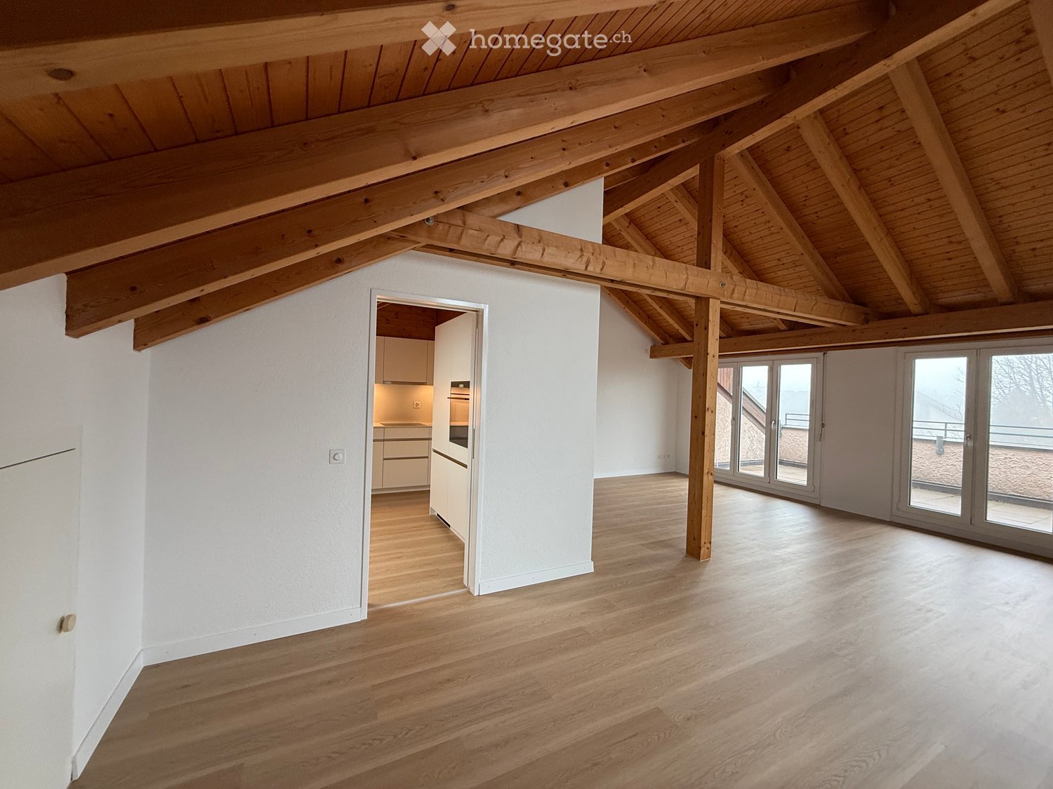 wooden beams, wooden floor, white walls, glass doors, kitchen area, empty room