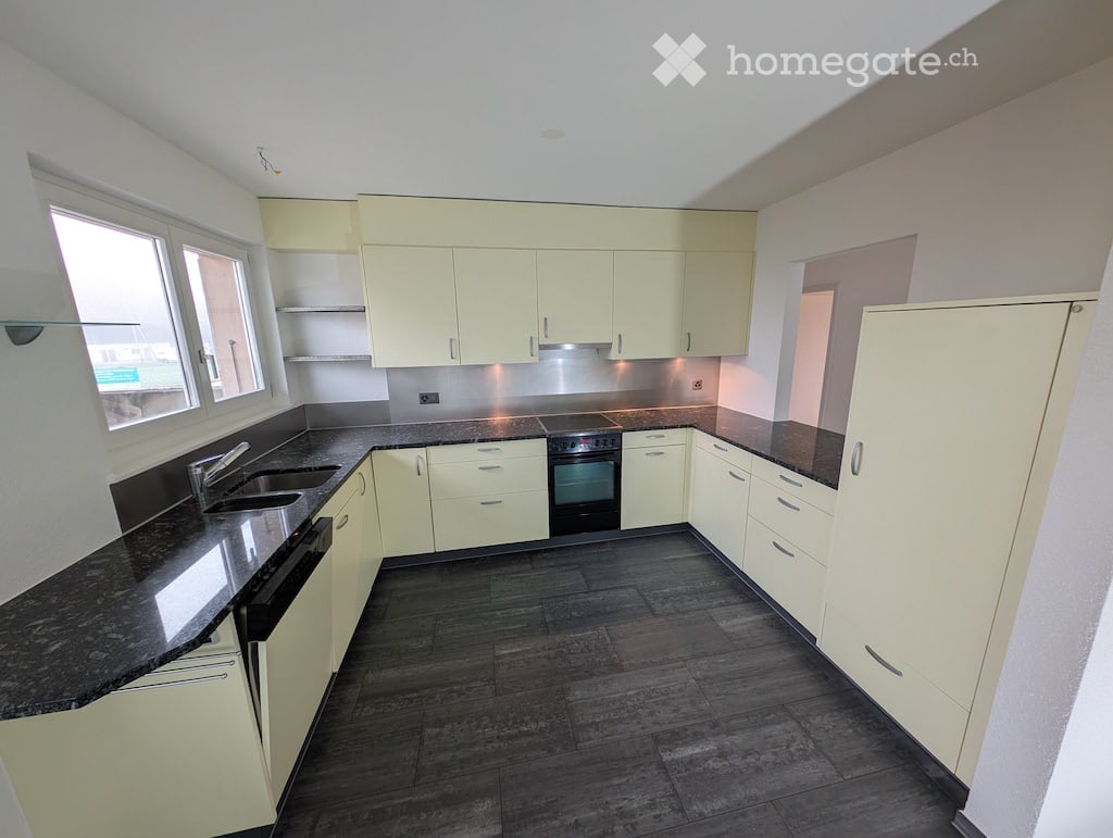 modern kitchen with cream cabinetry, granite countertops, integrated appliances, double sink, spacious