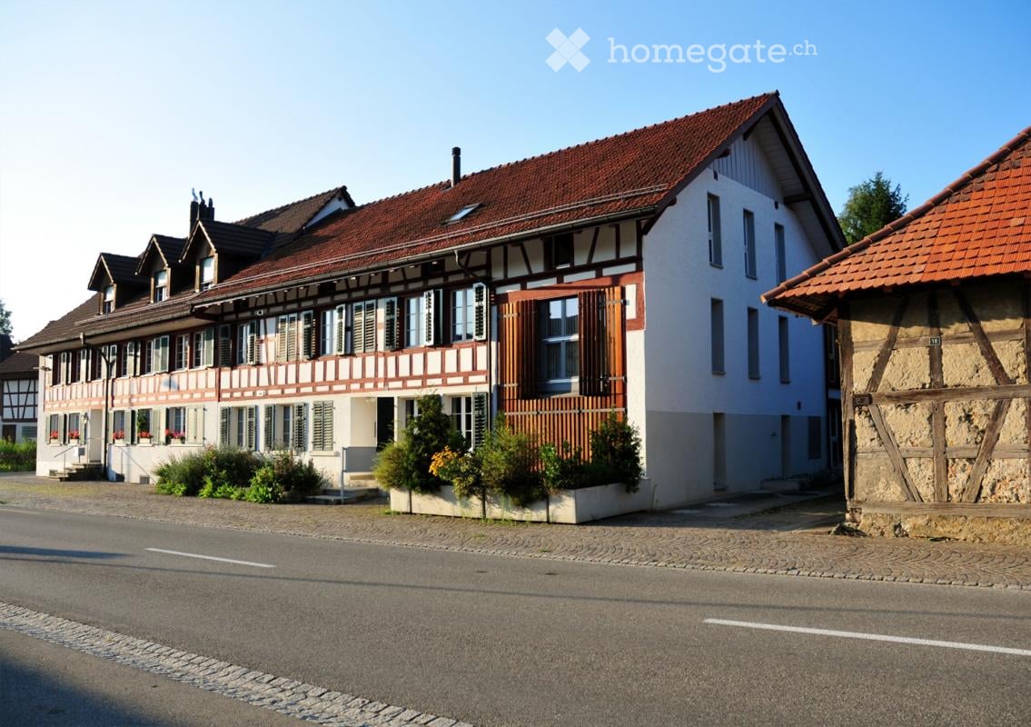 red roof, white walls, many windows, beige brick design, street, plants in front, brick road