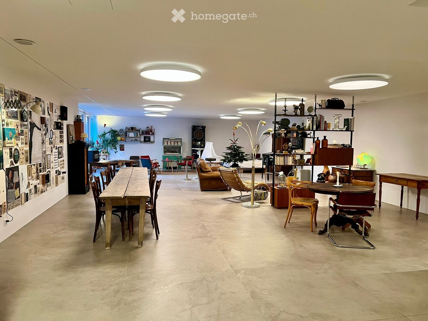 wide room, wooden table, chairs, decorative items on the wall, circular lights in the ceiling
