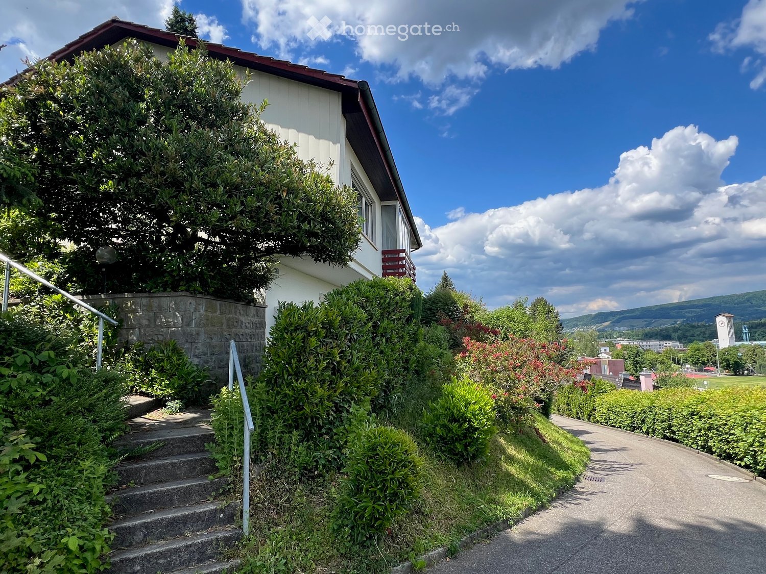 Single-family house with raised ground floor, modern architectural design, brick walls, wooden roof, steps leading up to the entrance