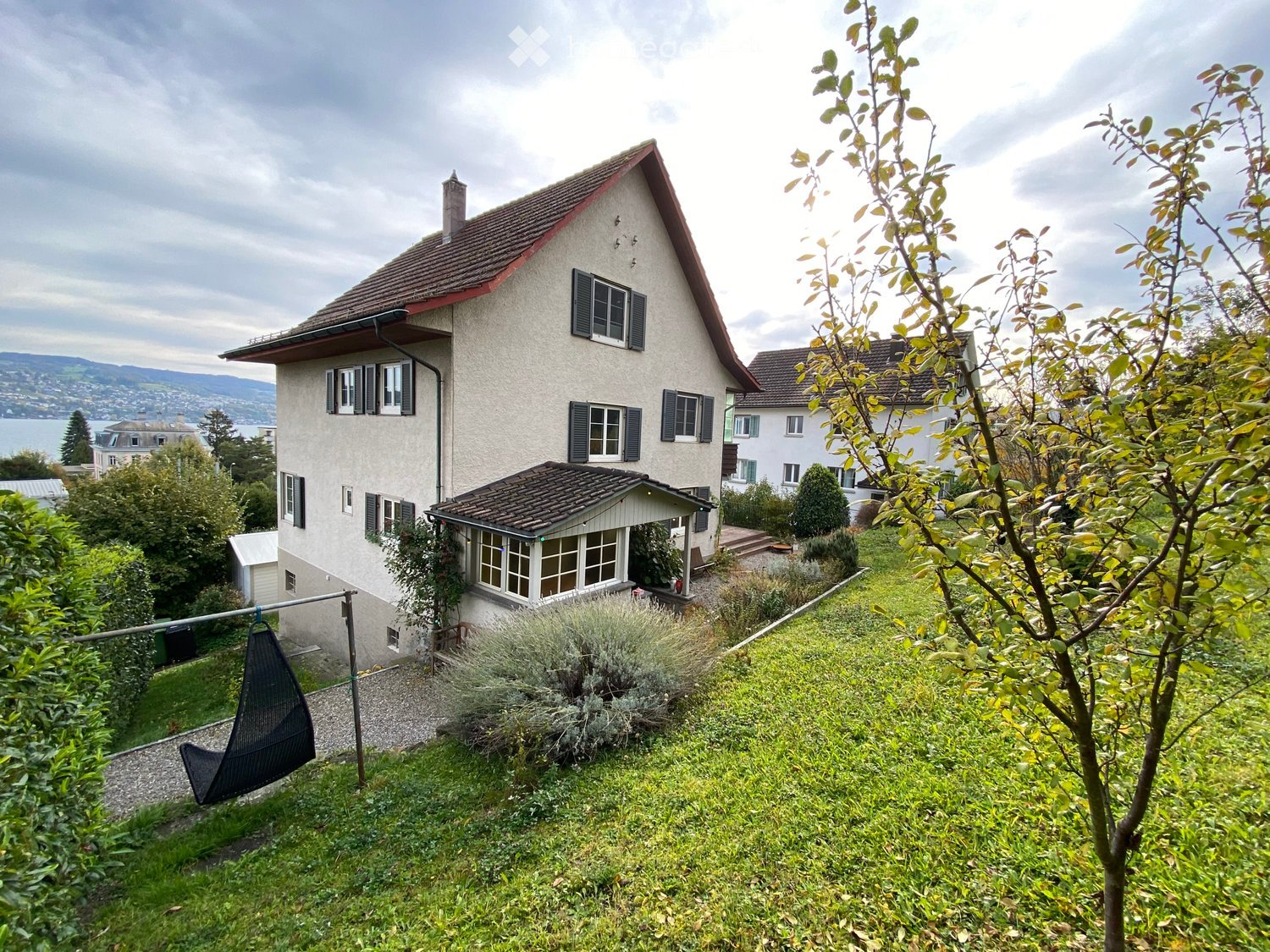 Large house with a raised ground floor, located on a slope with a beautiful view, two storeys, surrounded by greenery and water