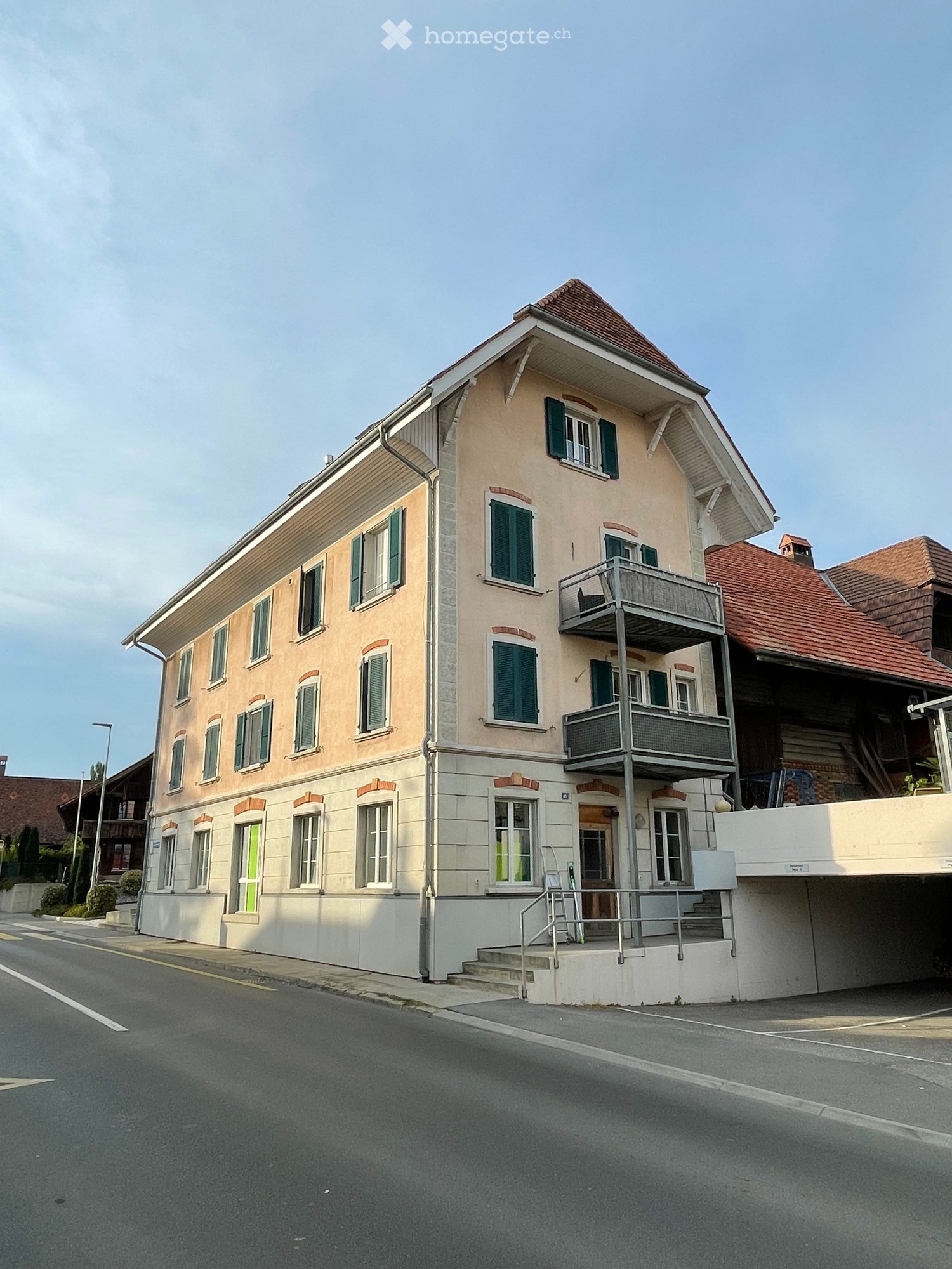 3-story building, beige facade, green shutters, entrance with steps, balcony on the second floor