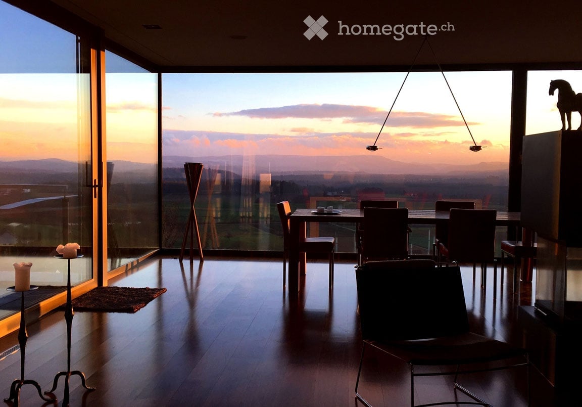 dining area with a view to the sunset, wooden floor, floor to ceiling glass walls, chandelier, dining table and chairs, horse statue