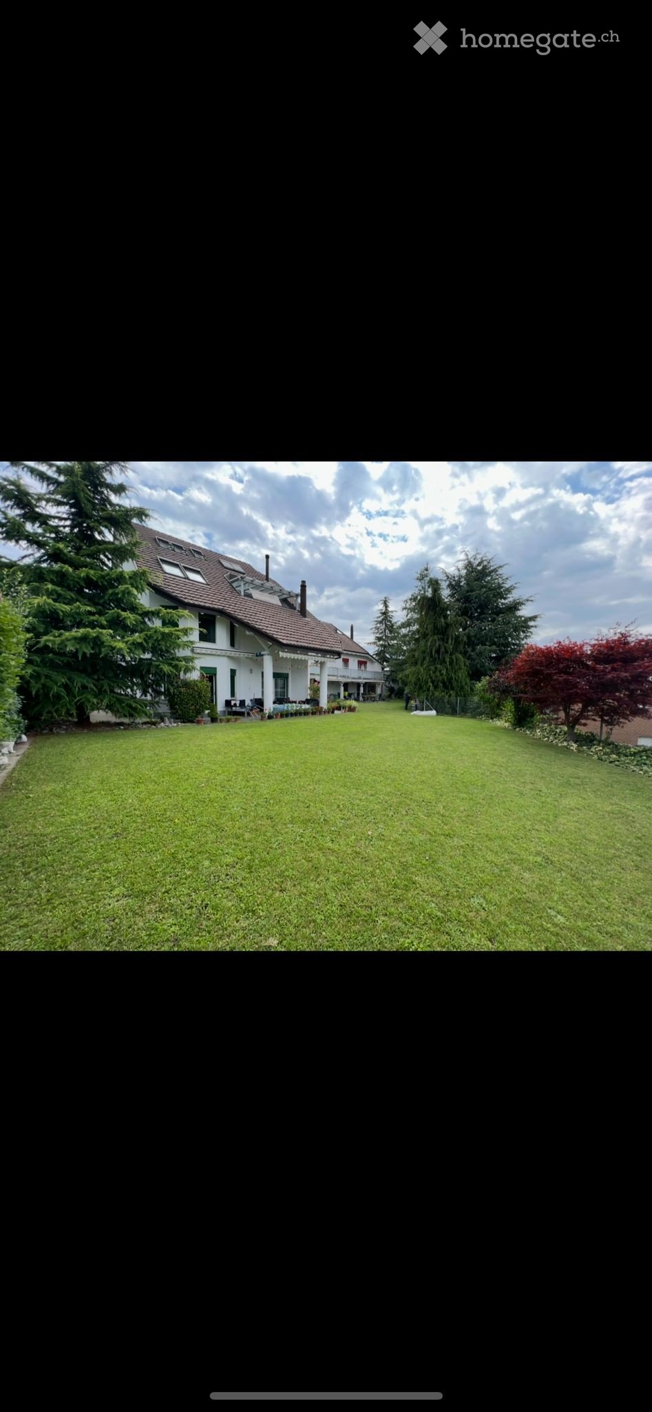Large house, brown roof, large lawn, trees, plants