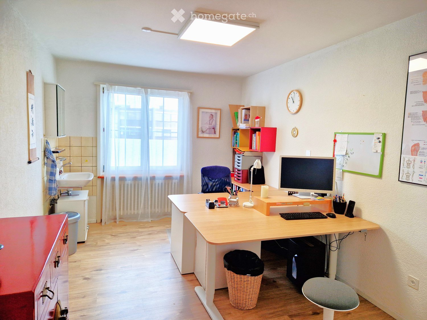 A room with a desk, computer, chair, cabinet, radiator, and decorative items.