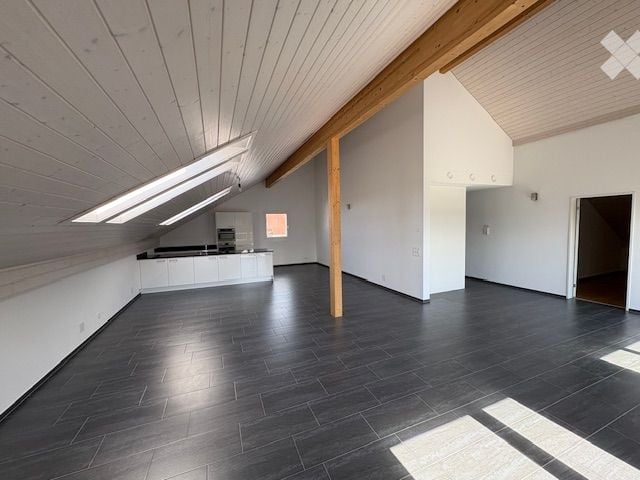 spacious room, wooden beams, white walls, wooden flooring, white cabinets, windows