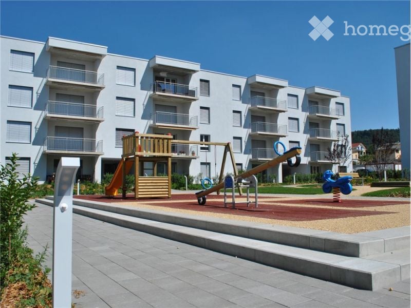modern apartment building with balconies, children's playground with slide and swing