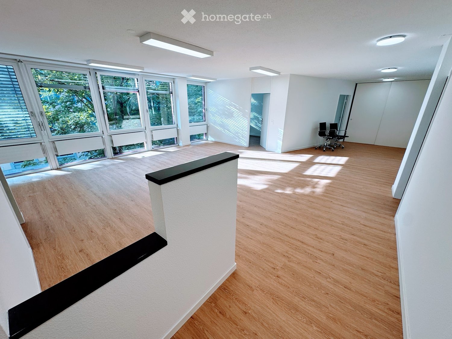 wooden floor, white walls, large windows, chairs, bright room