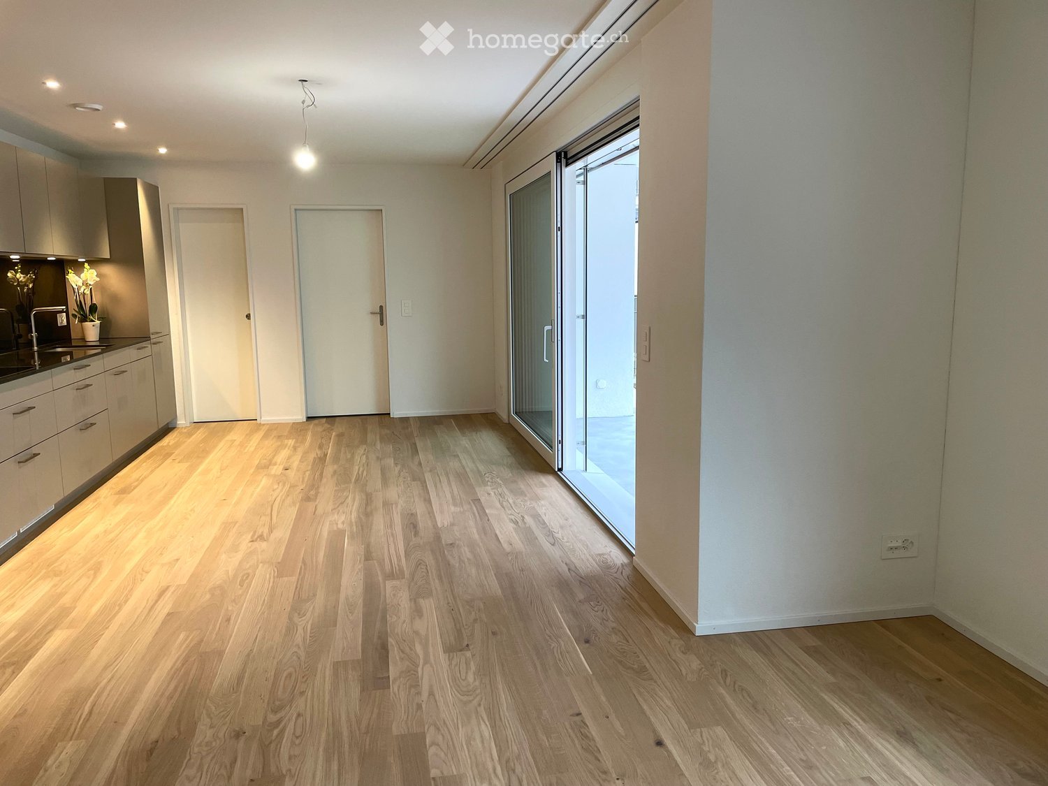 empty room, glass door, wooden floor, white walls, cabinets, countertop, light