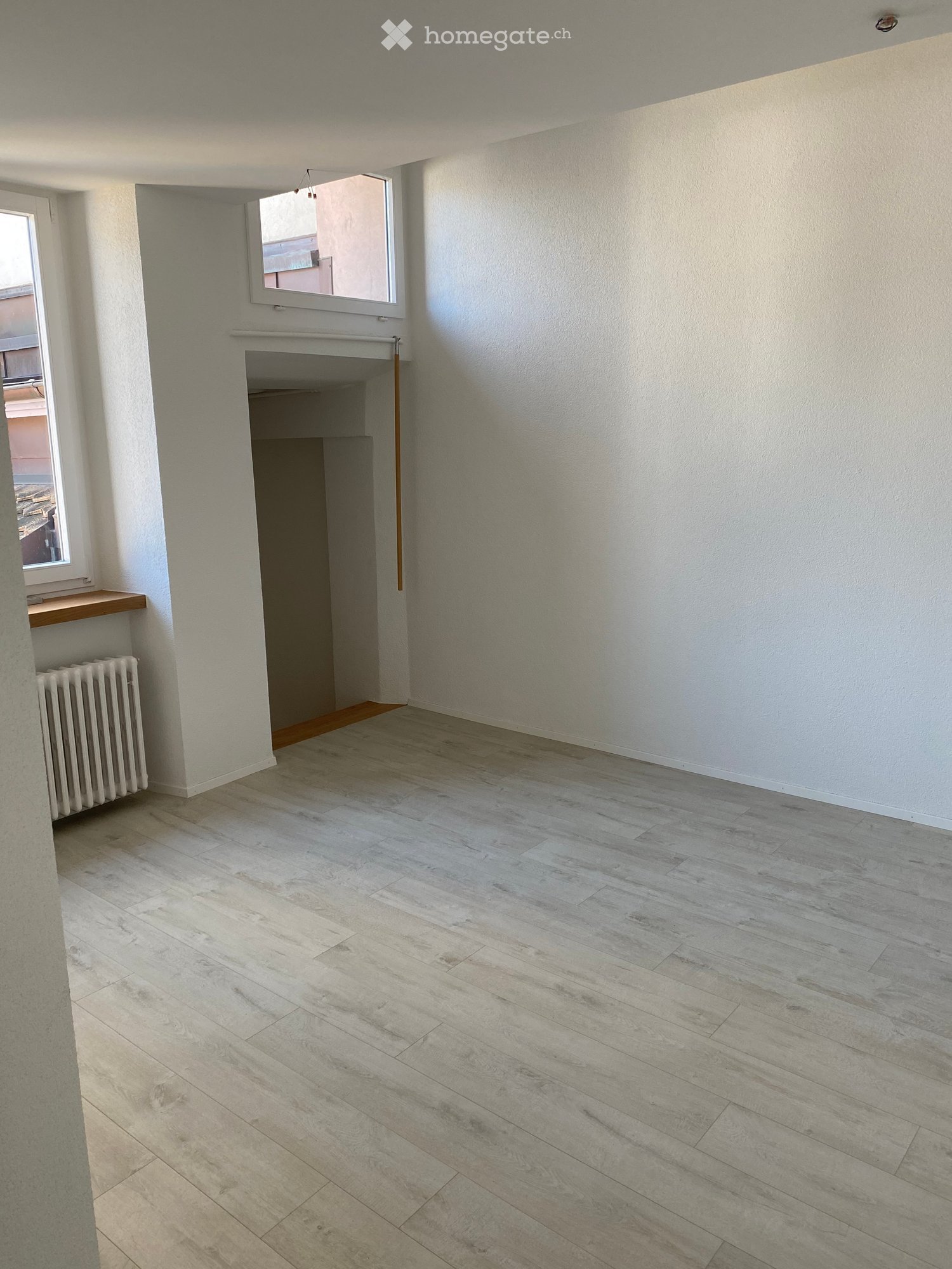 Empty room, tiled floor, white walls, two windows, wooden windowsill, radiator, small entranceway