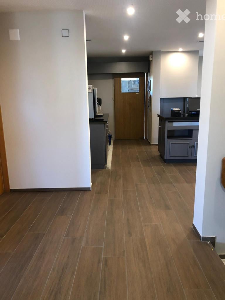 Wooden floors, white walls, open door, counter with monitor and printer, modern design.