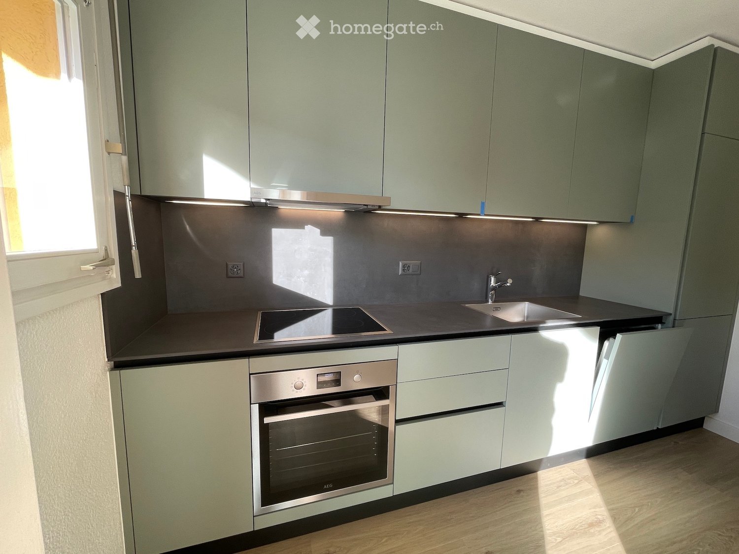 modern kitchen, light green cabinets, black granite countertop, built-in electric oven, induction stove, stainless steel sink, faucet