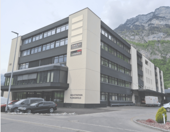 Office building, 4 stories, white and grey walls, glass windows, sign 'PIONTEX', parking lot