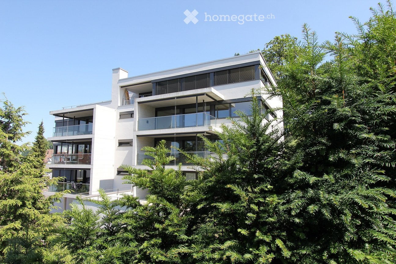 White contemporary building with several levels, glass railings on terraces