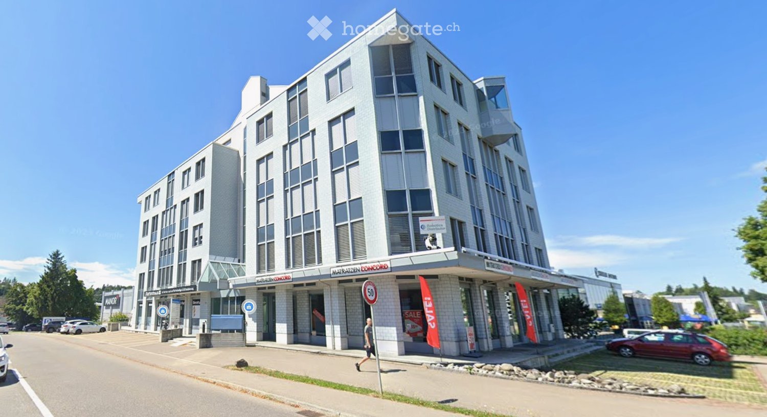 white modern office building, 5 floors, large windows, advertisement banners, parked cars