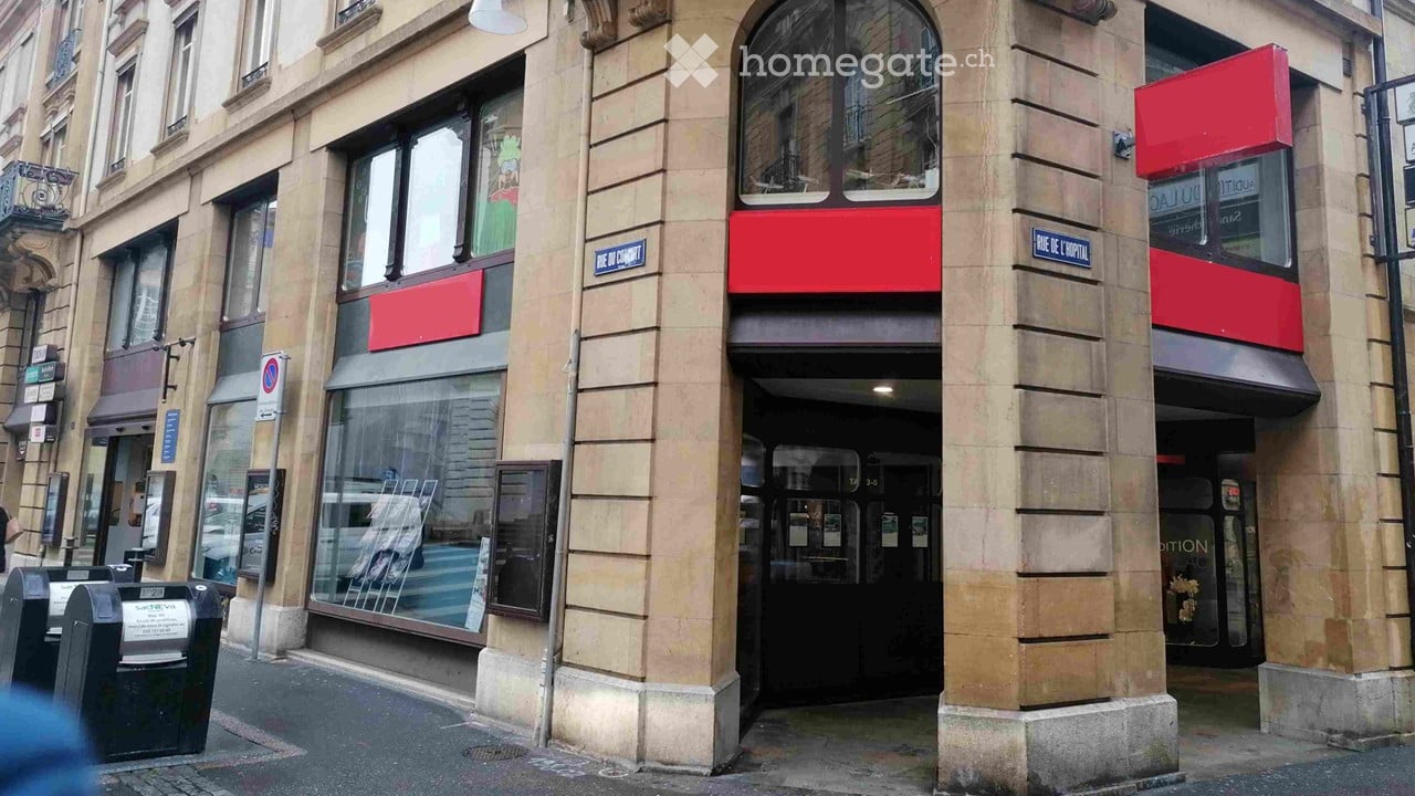 large beige building, large entrance, glass windows, red sign