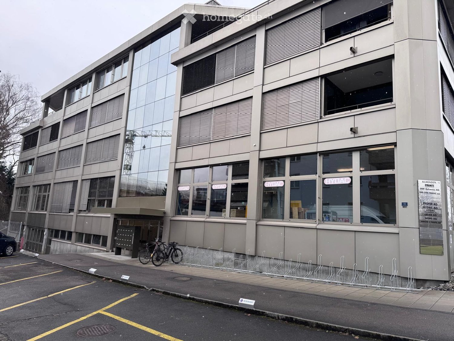 Multi-story office building with glass facade, multiple floors, two bicycles parked outside
