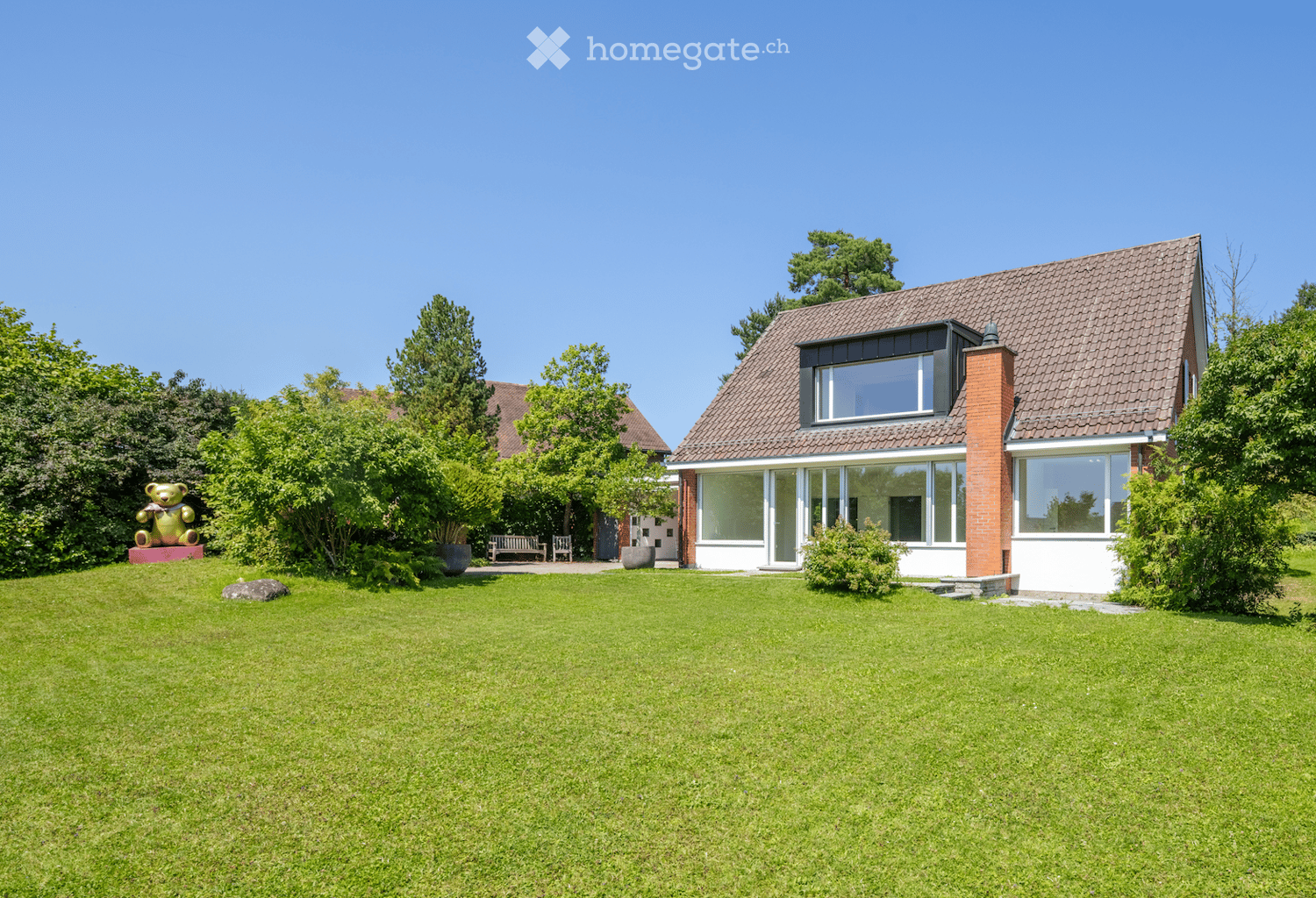 A detached house with a brown roof, glass windows, and a garden.