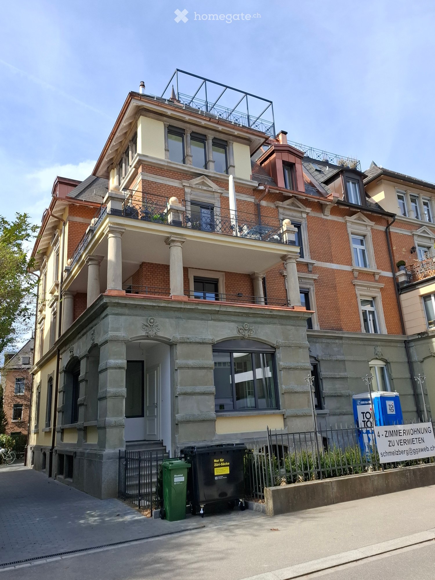 3 story building, brick facade, multiple balconies, large windows, entrance with stairs