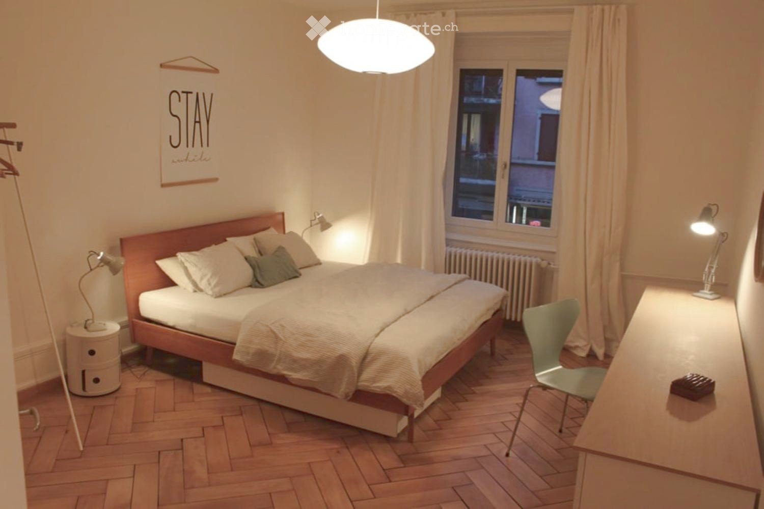 room with wooden floor, single bed, bedside lamps, desk, chair, radiator, wall art